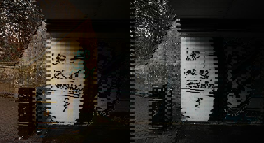 Underneath an overpass with graffiti on the wall saying "Lets love our community"